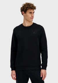 Sudadera negra fabricada en tejido suave, con un cuello redondo, puños acanalados y un diseño de logo sutil en el pecho.