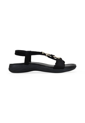 Sandalia negra para mujer con tiras elásticas traseras, suela acolchada y cadena metálica decorativa en las tiras superiores, mostrada de perfil.