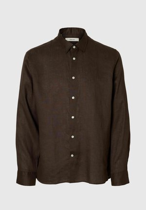 Chemise marron foncé à manches longues avec boutons, col pointu, boutons blancs et coupe ample sur un fond uni clair.