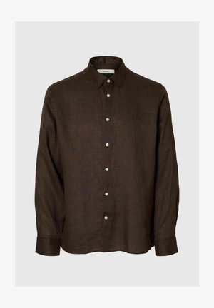 Chemise marron foncé à manches longues avec boutons, col pointu, boutons blancs et coupe ample sur un fond uni clair.