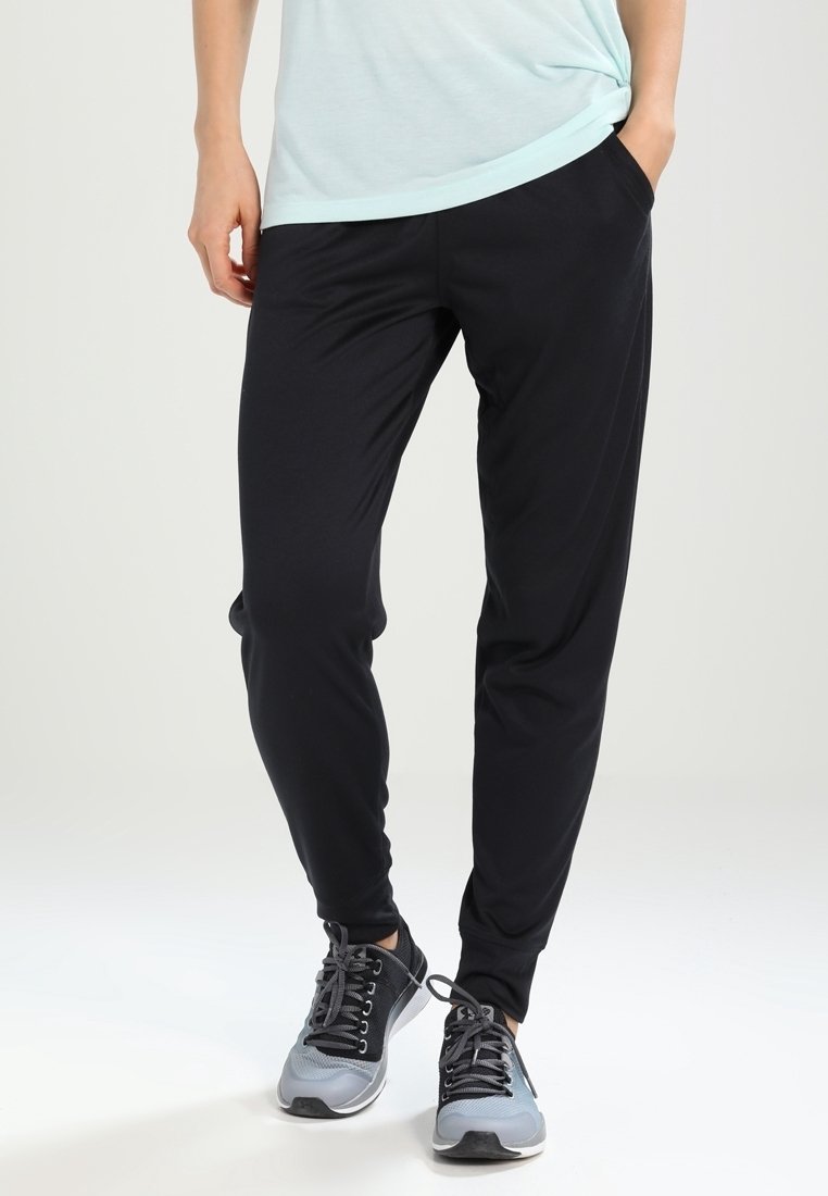 Svarta atletiska joggingbyxor i lätt tyg, med sidofickor och insvängda anklar. Matchade med grå löparskor.