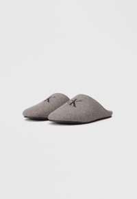 Papuci gri din fetru cu spate deschis, vârf ascuțit și logo-ul embosat „CK” în negru pe partea superioară. Textură moale și design minimalist.