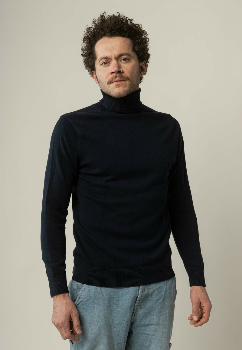 Navyblauwe coltrui met lange mouwen, gemaakt van een zachte stof. Beschikt over een geribde kraag en manchetten, een aansluitend ontwerp en een gladde textuur.