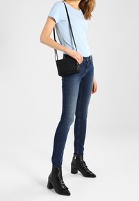 Vaaleansininen lyhythihainen t-paita, tummansiniset kapeat farkut, mustat nilkkurit, joissa on tukevat korot ja soljet, sekä musta olkalaukku.