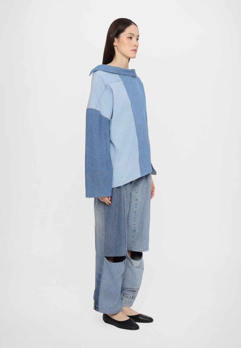 Denim outfit with a light blue and dark blue color block design; oversized top with a hood, baggy bottom with cut-out details.