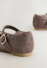 Trblietavé šošonové topánky v odtieni mauve s malým popruhom okolo členka a zlatým prackou. Plná podrážka s textúrovaným povrchom.