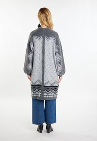 Cardigan lungo grigio lavorato a maglia con intricati motivi geometrici, caratterizzato da una vestibilità rilassata, maniche a palloncino e un design testurizzato.