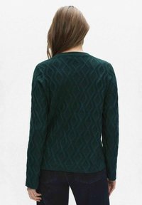 Donkergroene trui met een textuur van diamantpatroon, lange mouwen en een ronde hals. De achterkant toont verfijnde stikseldetails.