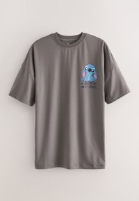 T-shirt gris à manches courtes avec un petit personnage de dessin animé bleu et le texte « Je ne fais pas les matins » sur le côté gauche de la poitrine.