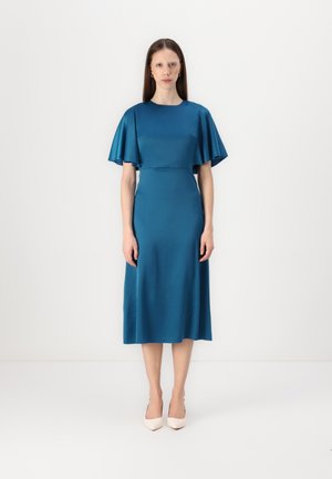 Teal satin dress with short, flutter sleeves, a fitted bodice, and a midi length skirt. Smooth texture, minimal design, paired with light-colored heels.