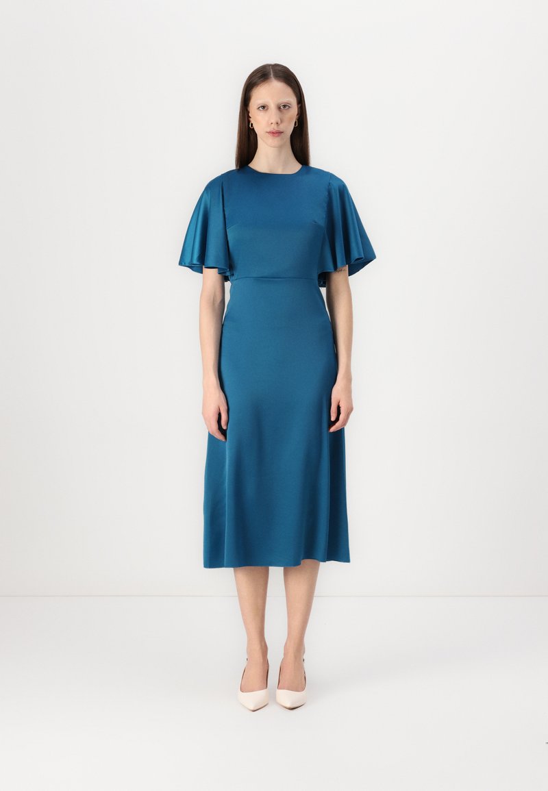 Robe en satin turquoise avec des manches courtes et légères, un corsage ajusté et une jupe midi. Texture lisse, design minimal, accompagnée de chaussures à talons de couleur claire.