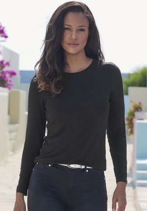 Schwarzes Langarmoberteil aus leichtem Stoff mit rundem Ausschnitt, kombiniert mit dunkelblauen Jeans und einem weißen Gürtel. Einfaches Design, keine Muster.