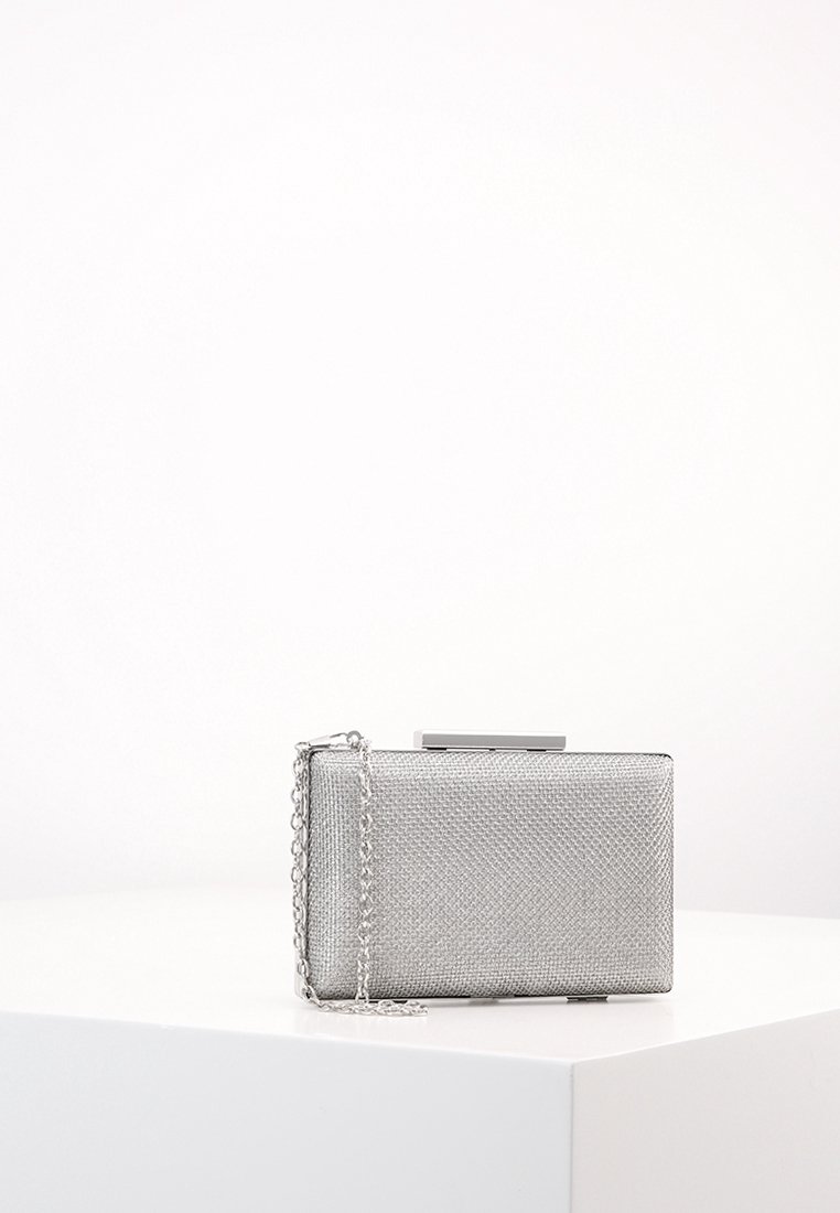 Lille rektangulær sølvfarvet clutch med tekstureret metaloverflade og tynd kædestrop, placeret på en hvid sokkel mod en ensfarvet baggrund.