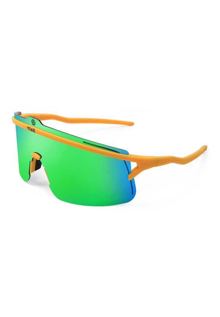 Lunettes de sport avec une grande lentille dégradée verte, une monture en caoutchouc orange et un nez ajustable. Conception légère et aérodynamique.