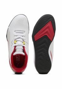 Zapatos deportivos blancos con parte superior perforada, acentos rojos y suela negra. Presentan un cierre de cordones amarillo y un forro interior suave para mayor comodidad.