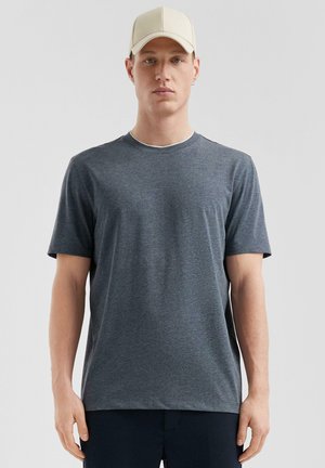 Gray short-sleeve t-shirt made of soft fabric, featuring a round neckline and a relaxed fit, worn with a light-colored cap.