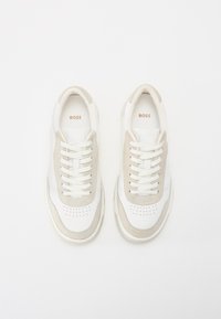 Sneaker bianche in pelle con accenti in suede beige, punta rotonda, design perforato sulla parte anteriore e lacci bianchi con marchio 'BOSS' sulla linguetta.