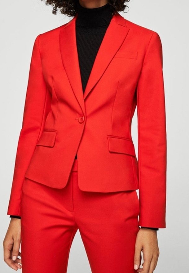 Červené na míru ušité sako s vykrojenými klopy a zapínáním na jeden knoflík; texturovaná látka, dvě přední kapsy, na míru zpracovaný střih, ve spojení s černým rolákem.