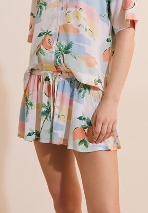 Light cotton outfit with tropical fruit and palm tree prints, featuring a buttoned shirt and gathered waist shorts on a person.