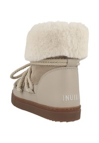 Botas de tobillo beige con un suave puño de piel de peluche, materiales de ante y cuero, cordones trenzados, suela texturizada y estampado en relieve de la marca "INUIKII".