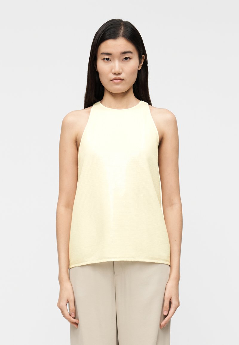 Κίτρινο αμάνικο τοπ με υφασμάτινη υφή και στρογγυλή λαιμόκοψη, με άνετη εφαρμογή και πλευρικές σχισμές για εύκολη κίνηση.