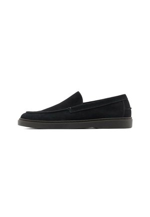 Mocassino slip-on in suede nero con tacco basso e punta arrotondata, mostrato di profilo su sfondo bianco.