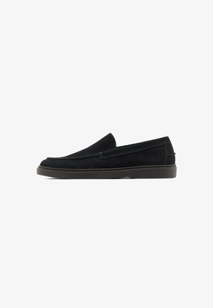Mocassino slip-on in suede nero con tacco basso e punta arrotondata, mostrato di profilo su sfondo bianco.