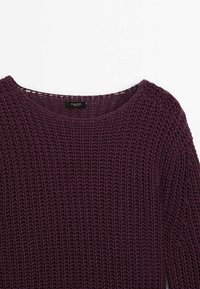 Maglione lavorato a maglia in un profondo viola con una trama a rete ampia e aperta. Presenta un colletto rotondo e una vestibilità rilassata. Etichetta visibile sul retro.
