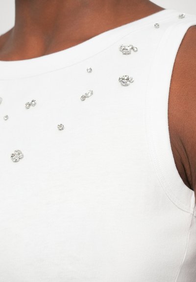 Fehér ujjatlan felső, kerek nyakkivágással, díszített szórt ezüst strasszokkal. Puha, sima anyag.