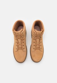 Tan semskede høye sneakers med avrundet tå, snøring foran, og teksturert polstring rundt ankelen. Har metalløyer og gummisåler.