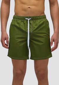 Pantaloni da mare verdi da uomo realizzati in un tessuto leggero, dotati di una vita elastica, laccetto bianco e dettagli di cucitura bianchi.