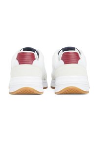 Białe buty sportowe z teksturowanymi skórzanymi akcentami w kolorze czerwonym oraz granatowym wewnętrznym wykończeniem. Posiadają jasnokolorową gumową podeszwę z wzorem bieżnika.