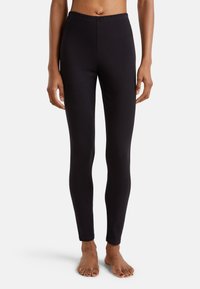 Leggings noirs en tissu extensible avec une taille élastique. Conception ajustée, texture lisse, longueur cheville, sans motifs visibles ni accessoires.