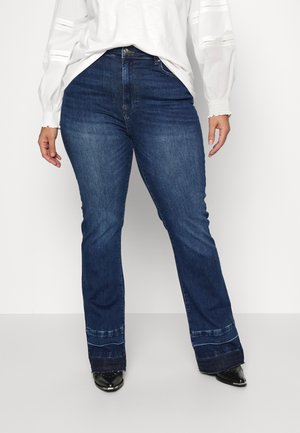 Jeans flare azul-escuro em lavagem média, apresentando um design clássico de cinco bolsos e costura contrastante na barra.