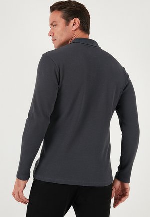 Gray long-sleeve polo shirt featuring a textured fabric, collar, and a straight hem. The design includes a fitted silhouette and minimal detailing.