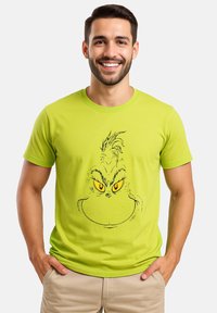 T-shirt di un brillante verde lime con maniche corte, caratterizzato da una grafica a contorno nero di un personaggio con occhi gialli e capelli a punte sul davanti.