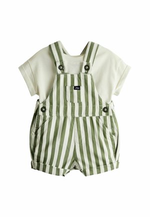Biela košeľa s krátkym rukávom v kombinácii so zeleno-bielymi vertikálne pruhovanými krátkymi nohavicami na traky s predným vreckom a patentkami na ramienkach.