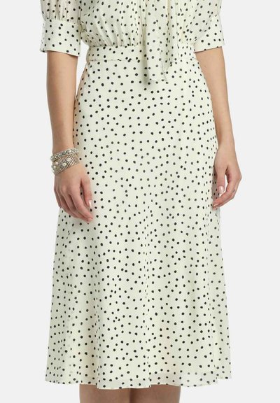 Fehér ruha fekete pöttyökkel, rövid, pufi ujjakkal, megkötős nyakkivágással és térd alá érő, bővített szoknyával. Sima anyagfelület.