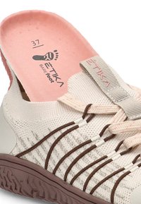 Zapatilla de punto color beige claro sin tacón con cordones elásticos marrones, plantilla rosa marcada con la talla 37 y la marca "ETIKA" en la lengüeta y en la plantilla.