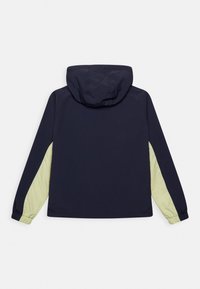 Granatowa kurtka wiatrówka z kapturem, z jasnokrajobrazowymi panelami na rękawach i elastycznymi mankietami dla pewnego dopasowania.