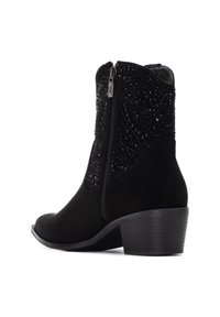 Botines de ante negros con parte superior texturizada, cortes decorativos y cremallera lateral. Tacón bajo en bloque. Acabado suave y mate.