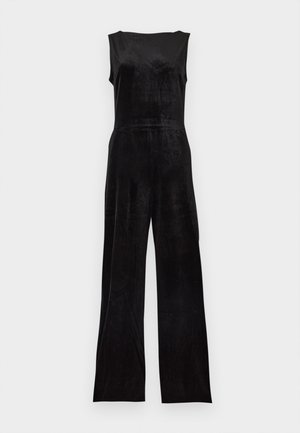 Combinaison en velours noire sans manches avec jambes larges, taille cintrée et encolure ronde, présentée sur un fond clair uni.