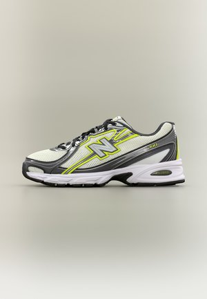 Scarpa da corsa bianca e grigia con lacci neri, accenti giallo neon e suola ammortizzata, mostrata in profilo laterale su uno sfondo neutro.