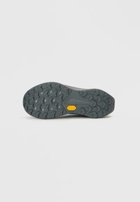 Vibram-zool met een gestructureerde, gepatenteerde grip. Grijze rubberen zool met een geel accent. Ontworpen voor grip en duurzaamheid in buitenomstandigheden.