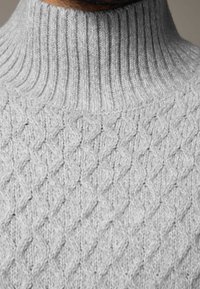 Hellgrauer Strickpullover mit geripptem Rollkragen. Verfügt über ein strukturiertes Diamantmuster über den gesamten Körper, das dickes, weiches Garn zur Schau stellt.