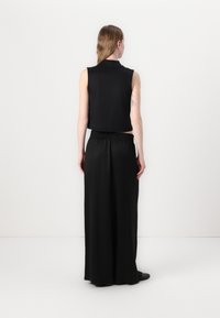 Black sleeveless top and flowy black pants; soft fabric, relaxed fit, elastic waistband, and minimalist design. No visible patterns or accents.