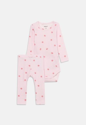 Lichtroze babybody met lange mouwen en legging, bedrukt met kleine rode aardbeitjes, plat gelegd op een witte achtergrond.