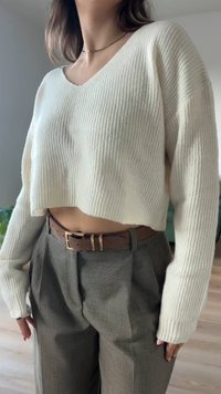 Kremna rebrasta skrajšana jopica z dolgimi rokavi, kombinirana z modrimi hlačami visoko v pasu. Rjavi pas ima podrobnost kovinske sponke.