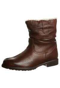 Botte cheville en cuir marron avec semelle en caoutchouc plate et doublure en laine blanche visible au niveau du bord supérieur, conçue pour les temps froids.