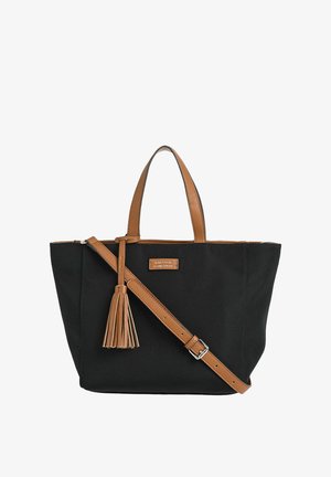 Sac cabas noir avec poignées en cuir marron, sangle d'épaule réglable, détail pompon et petite étiquette logo rectangulaire à l'avant.